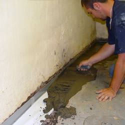 A basement waterproofer installing a perimeter drain system in Clemmons